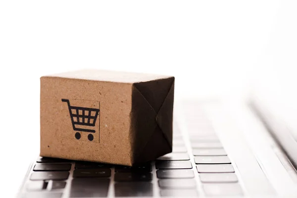 Primer plano de caja de cartón de juguete en el teclado del ordenador portátil aislado en blanco, concepto de comercio electrónico - foto de stock