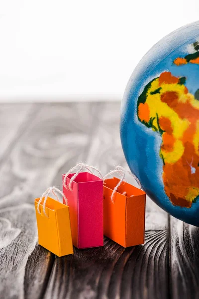 Bolsas de compras de juguete cerca del globo en la mesa aislado en blanco, concepto de comercio electrónico - foto de stock