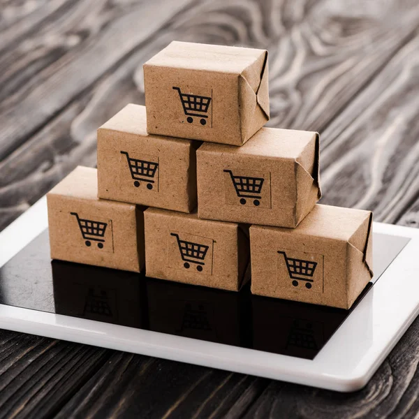 Primer plano de cajas de cartón de juguete en tableta digital, concepto de comercio electrónico - foto de stock