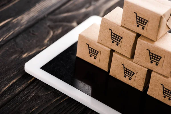 Selective focus of small carton boxes on digital tablet, e-commerce concept — Stock Photo