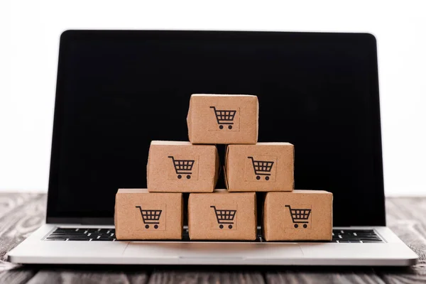 Cajas de cartón de juguete en el ordenador portátil con pantalla en blanco aislado en blanco, concepto de comercio electrónico - foto de stock