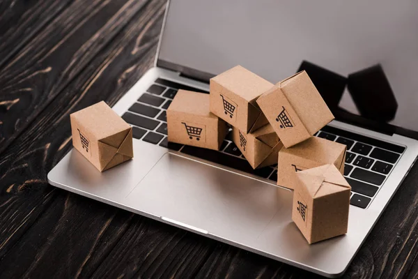 Cajas de cartón pequeñas en el ordenador portátil con pantalla en blanco, concepto de comercio electrónico - foto de stock