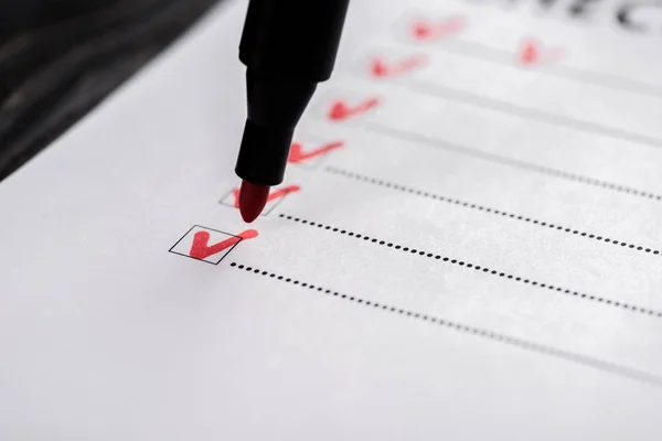 Gros plan de la liste de vérification avec tiques près du stylo marqueur rouge — Photo de stock