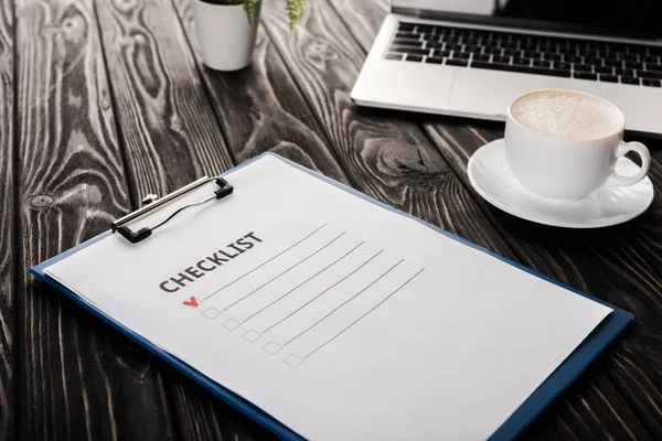 Selective focus of clipboard with checklist near laptop and cup of coffee on table, e-commerce concept — Stock Photo