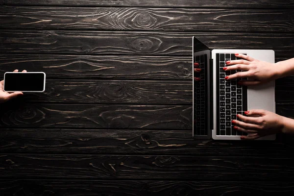 Vista dall'alto della donna d'affari che tiene smartphone con schermo vuoto vicino al collega utilizzando laptop, concetto di e-commerce — Foto stock