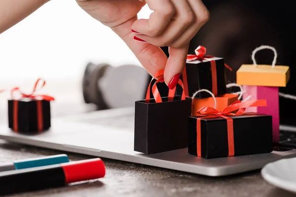 Abgeschnittene Ansicht einer Frau, die Spielzeug-Einkaufstüten in der Nähe von Laptop auf weißem Hintergrund berührt, E-Commerce-Konzept — Stockfoto