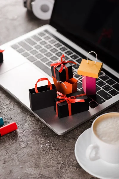 Selective focus of shopping bags near laptop, cup of coffee and marker pens, e-commerce concept — Stock Photo