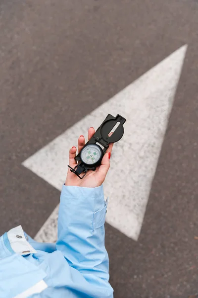 Ansicht von oben: Frau hält Kompass in der Nähe der Straße — Stockfoto