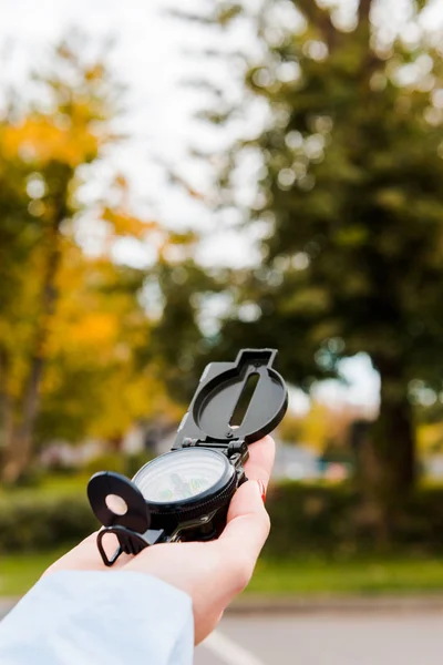 Cropped view of woman holding compass in autumnal park — Stock Photo