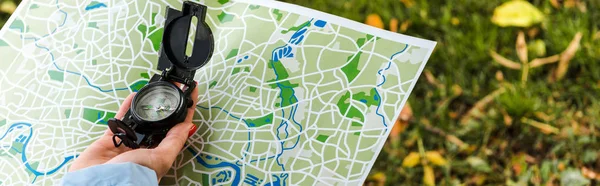 Panoramic shot of woman holding map and vintage compass outside — Stock Photo