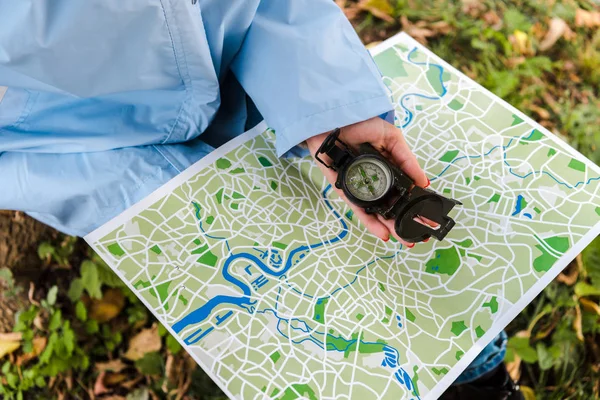 Ausgeschnittene Ansicht des Reisenden, der Karte und Kompass draußen hält — Stockfoto