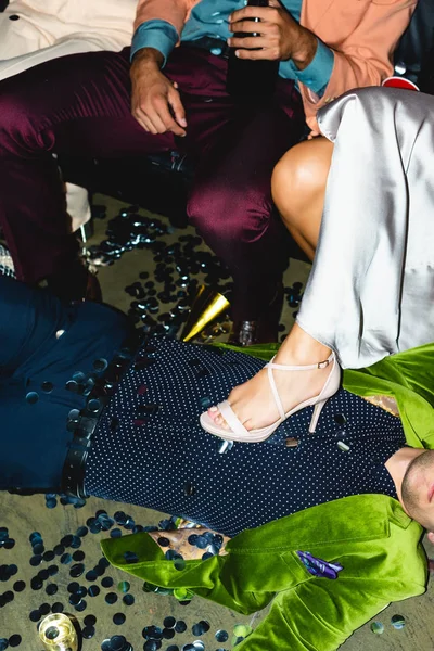 Cropped view of drunk man lying on floor near friends — Stock Photo