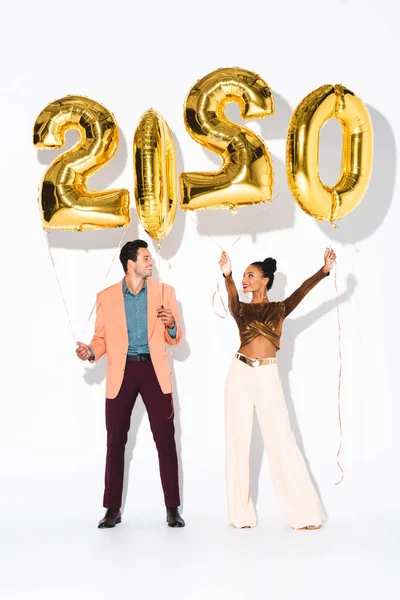 Cheerful man and african american girl standing near balloons on white — Stock Photo