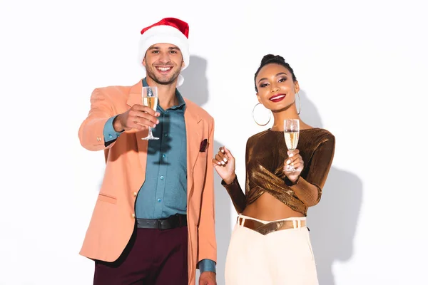 Allegra donna afroamericana in piedi con l'uomo in cappello di Babbo Natale in possesso di bicchiere di champagne su bianco — Foto stock