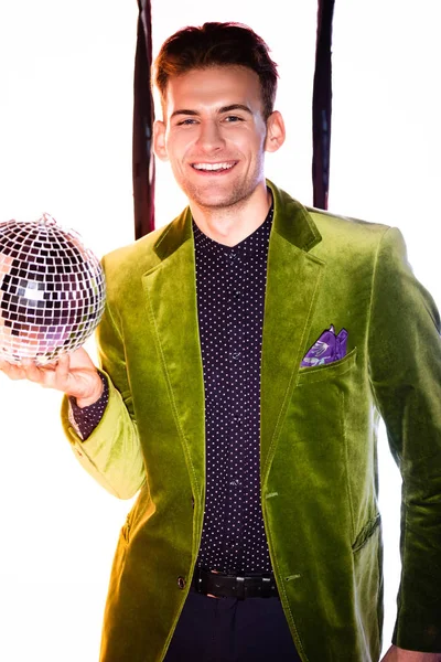 Счастливый человек в зеленом пиджаке, держащий блестящий диско-шар на белом с черными полосами — стоковое фото