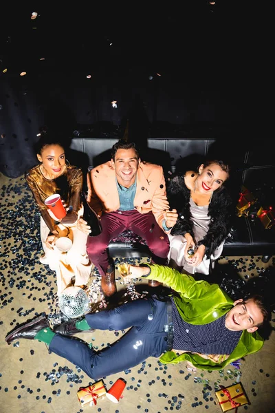 Overhead view of cheerful multicultural friends holding drinks near disco ball — Stock Photo