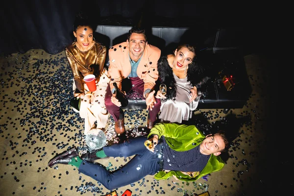 Над головой вид веселых мультикультурных мужчин и женщин, держащих напитки возле дискотечного бала — стоковое фото