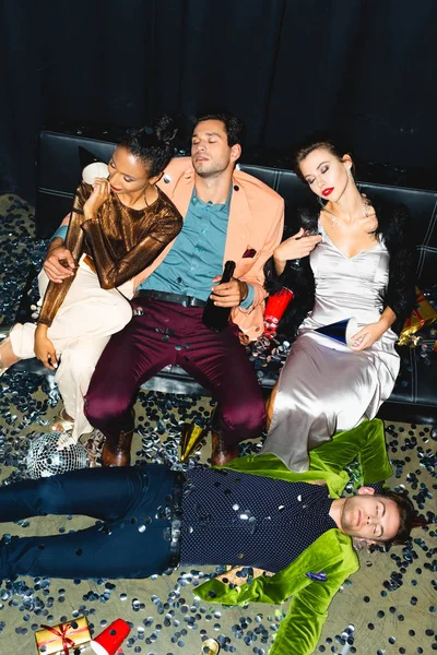 Overhead view of tired multicultural friends sleeping on sofa near disco ball — Stock Photo