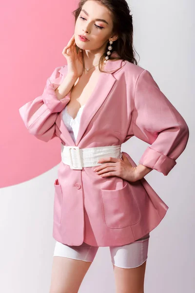 Stylisches Mädchen, das mit der Hand an der Hüfte auf weiß und rosa steht — Stockfoto