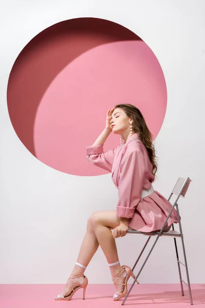 Красива дівчина сидить на стільці на білому і рожевому — стокове фото