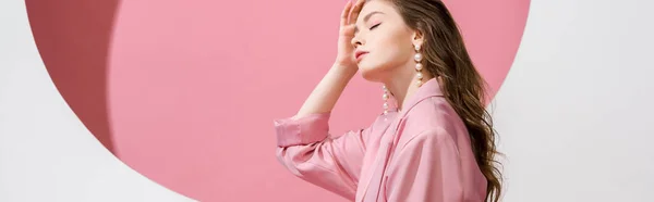 Colpo panoramico di bella ragazza toccando i capelli su bianco e rosa — Foto stock