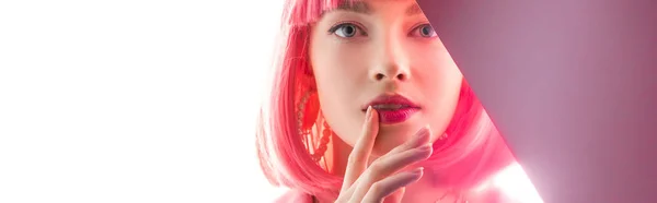 Plano panorámico de mujer atractiva tocando los labios y mirando a la cámara en blanco y rosa - foto de stock