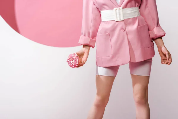 Cropped view of woman standing holding sweet doughnut on white and pink — Stock Photo