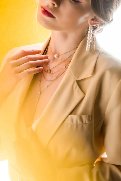 Vista ritagliata della donna toccando collana su bianco e giallo — Foto stock