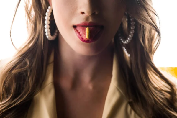 Vista ritagliata della donna che sporge la lingua con pillola gialla sul bianco — Foto stock