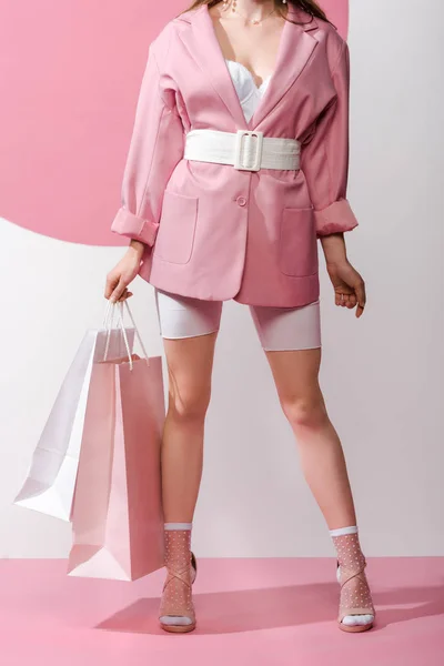 Обрізаний вид стильної дівчини, що тримає сумки на білому та рожевому — стокове фото