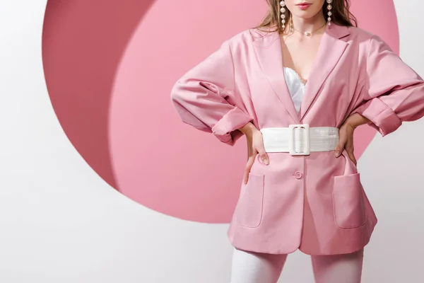 Cropped view of stylish woman standing with hands on hips on white and pink — Stock Photo