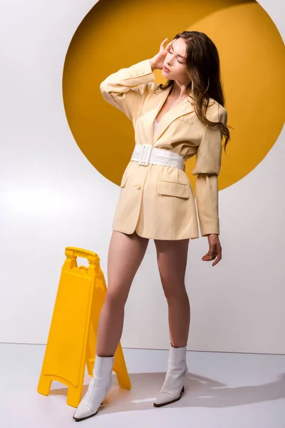 Stylische Frau steht neben gelbem Brett auf weiß und orange — Stockfoto
