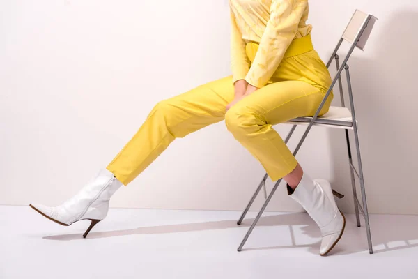 Vista cortada da jovem mulher sentada na cadeira no branco — Fotografia de Stock