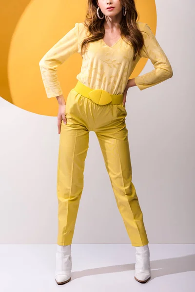Vista ritagliata della donna in piedi con le mani sui fianchi su arancione e bianco — Foto stock
