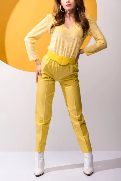 Cropped view of woman standing with hands on hips on orange and white — Stock Photo