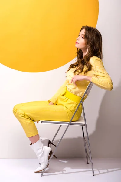 Приваблива жінка сидить на стільці на помаранчевому і білому — стокове фото