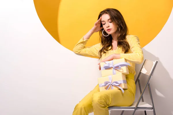 Mujer atractiva mirando los regalos en naranja y blanco - foto de stock