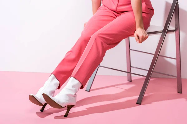 Cropped view of woman in boots sitting on white and pink — Stock Photo