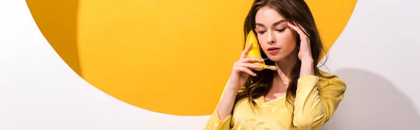 Panoramic shot of young woman holding banana on white and orange — Stock Photo