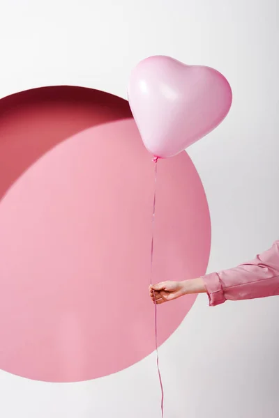 Vue recadrée de la femme tenant un ballon sur rose et blanc — Photo de stock