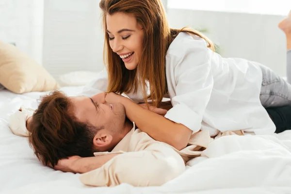 Attractive and smiling girlfriend hugging handsome boyfriend in apartment — Stock Photo