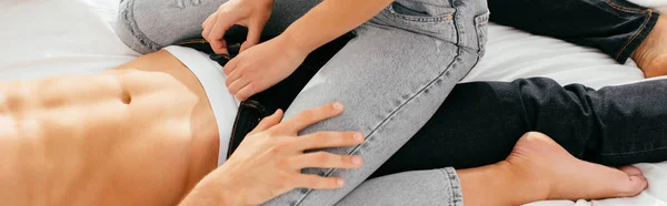 Panoramic shot of girlfriend unbuttoning trousers of boyfriend in apartment — Stock Photo