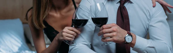 Panoramic shot of girlfriend and businessman clinking with wine glasses in apartment — Stock Photo