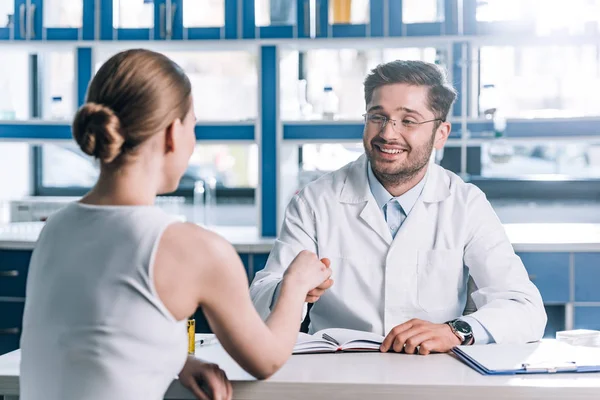 Selective focus of happy doctor in glasses shaking hands with woman — Stock Photo