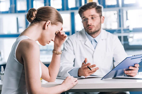 Selective focus of upset woman sitting near allergist in clinic — Stock Photo