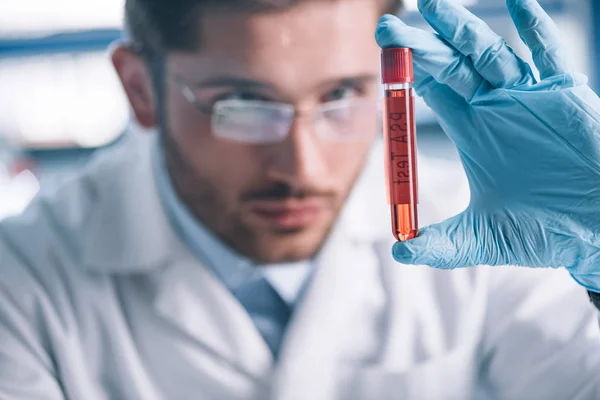 Selective focus of bearded immunologist holding test tube with red liquid — Stock Photo