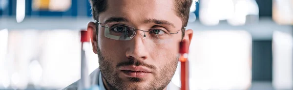 Inyección panorámica de un inmunólogo guapo mirando los tubos de ensayo - foto de stock