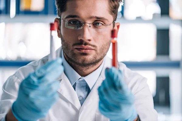 Selective focus of handsome immunologist holding test tubes — Stock Photo