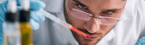 Panoramic shot of immunologist holding pipette with red liquid — Stock Photo