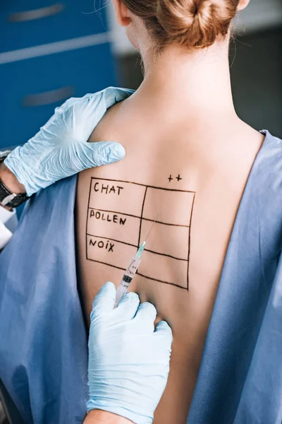 Cropped view of allergist holding pipette near patient with letters on marked body — Stock Photo